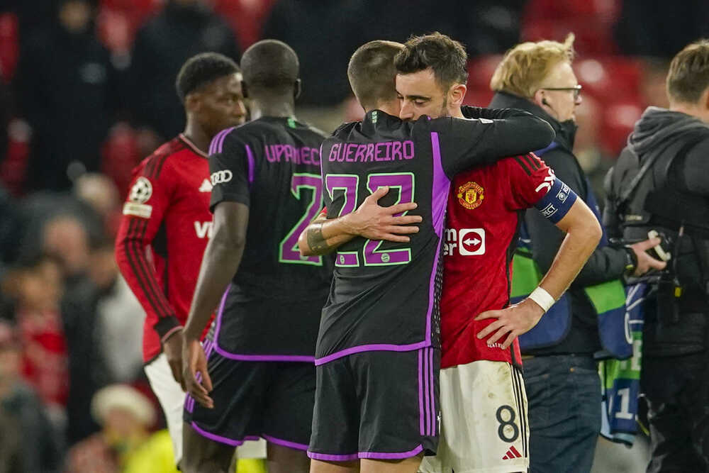Futbalista Bayernu Mníchov Raphaël Guerreiro (vľavo) a hráč Manchestru United Bruno Fernandes sa objímajú po zápase.