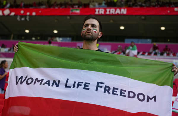 Futbalový fanúšik drží iránsku vlajku na podporu slobodu žien v Iráne pred zápasom základnej B-skupiny Wales - Irán.