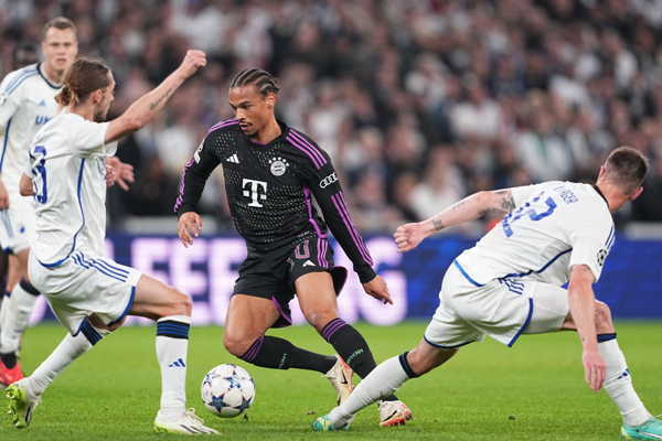 Futbalista Bayernu Leroy Sané (uprostred) a hráč Kodane Lukas Lerager (vpravo) bojujú o loptu.