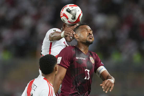 Futbalista Peru Pedro Aquino (uprostred) a hráč Venezuely Yordan Osorio (vpravo) bojujú o loptu.