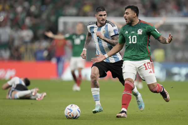 Mexický hráč Alexis Vega (vpravo) uteká s loptou pred Argentínčanom Rodrigom De Paulom.