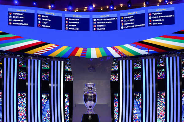 Trofej umiestnená pred tabuľou, na ktorej sú znázornené vyžrebované tímy počas žrebu finálového turnaja EURO 2024.